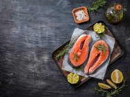 Dois bifes de salmão crus frescos em papel com sal, pimentão, limão e alecrim — Fotografia de Stock