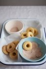 Baked mini vanilla doughnuts being dipped in cinnamon sugar — Stock Photo