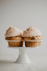 Cupcakes rematados con crema de mantequilla en un pequeño soporte de cerámica - foto de stock