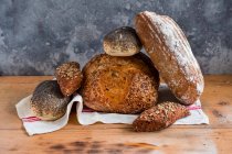 Різні хлібні хліби з тканиною на дерев'яній поверхні — стокове фото