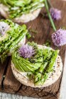 Avocado rose and blanched asparagus on rice crackers — Stock Photo