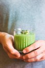 Grüner veganer Smoothie mit Spinat, Banane und Keimlingen im Glas in Männerhand — Stockfoto