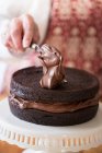Una torta in fase di realizzazione: crema di cioccolato che viene spalmata su una torta — Foto stock