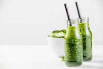 Frullato verde e ciotola bianca di spinaci sul tavolo bianco — Foto stock