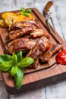 Delicious Grilled Pork Ribs and Fried Potatoes with Sauce on wooden cutting board — Stock Photo