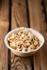 Gilded popcorn in a bowl on a wooden surface — Fotografia de Stock