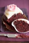 Half a chocolate cupcake with vanilla cream and a sugar rose — Stock Photo