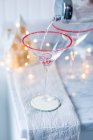 Uma bebida sendo derramada em um copo Martini sobre um bombom de Natal — Fotografia de Stock