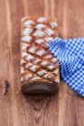Wheat bread on wooden surface with checkered cloth — Stock Photo