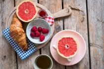 Frühstück mit Croissants, Marmelade, Himbeeren und Grapefruithälften — Stockfoto