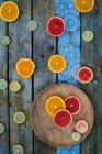 Arance, lime e pompelmi fette su piatto e superficie in legno — Foto stock