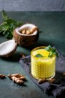 Glass of ayurvedic drink golden coconut milk turmeric iced latte with curcuma powder, mint and ingredients — Stock Photo