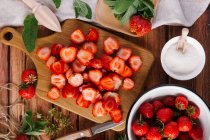 Fresh strawberries, cleaned and sliced, sugar and mint leaves — Stock Photo
