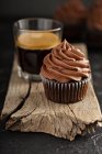 Dunkle Schokolade Cupcakes mit Ganache Zuckerguss auf dunklem Hintergrund mit Espresso im Glas — Stockfoto