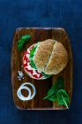 Healthy vegetarian sandwich with feta cheese, tomatoes, basil and pepper served on wooden chopping board over vintage background — Stock Photo