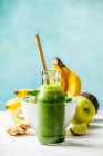 Batido verde e ingredientes en la mesa contra la pared - foto de stock