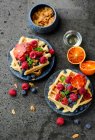 Banana waffles with fresh berries, blood oranges and coconut chips — Stock Photo