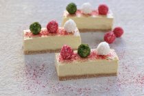 Raw mango and coconut cheesecake slices decorated with raspberry powder and coconut balls (vegan) — Stock Photo