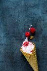 Raspberry ice cream in a cone on a blue grey surface — Stock Photo