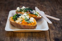 Фаршированная сладкая картошка со шпинатом, красным луком, кускусом, сыром фета и кориандром — стоковое фото