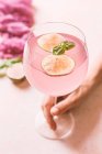 Frau hält rosa Cocktail mit Feige und Basilikum in der Hand — Stockfoto