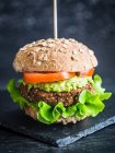Vegan red beans and quinoa burger sandwich with guacamole, fresh lettuce and tomatoes, served on a whole grain bun — Stock Photo