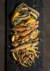 Assortimento di pesce fritto con spicchi di limone e prezzemolo su tavola di ardesia e fondo scuro — Foto stock