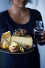 Una donna con un vassoio di formaggio alle erbe selvatiche, pane e chutney — Foto stock
