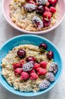 Two bowls of porridge with cherries, raspberries and frozen blackberries — Stock Photo