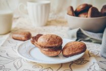 Шоколадне глазуроване м'яке імбирне печиво на білій тарілці, миска з печивом та молоко — стокове фото