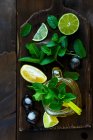 Зеленый чай с лаймом, лимоном и мятой в стеклянном кувшине на деревянной доске — стоковое фото