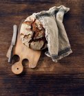 Um pão crocante numa tábua de madeira — Fotografia de Stock