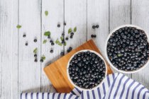 Fresh blueberries in bowls on a wooden background — Stock Photo