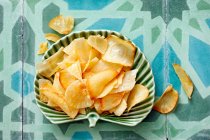 Свіжі запечені картопляні чіпси з сиром і лимоном на синьому фоні . — стокове фото