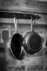 Антикварные сковородки, висящие на деревянной балке — стоковое фото