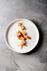 Соленые карамельные конфеты с карамельным соусом в белой тарелке на сером фоне — стоковое фото