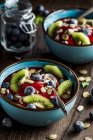 Bowl of berries smoothie with fresh blueberries, kiwi, pumpkin and sunflower seeds on top — Stock Photo