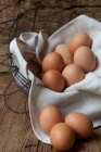 Fresh eggs on a cloth in a wire basket — Stock Photo