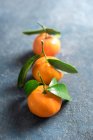 Mandarins with green leaves on stone surface — Stock Photo