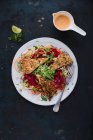 Индейка эскалоп с ореховой коркой со свеклой рисовой лапшой, Джулиеной морковью и салатом из трав и креветок — стоковое фото