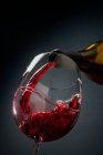 Red wine poured from a bottle into a glass — Foto stock