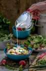 Dressing being poured over a salad with radishes and boiled eggs — Stock Photo