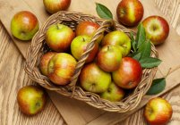 Fresh Cox apples with leaves in a basket — Stock Photo