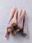 Несколько фиолетовых морковок на каменной поверхности — стоковое фото