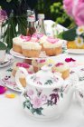 Кексы с лепестками роз на стол, накрытый на чай — стоковое фото