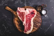 A raw T-bone steak on a wooden board — Stock Photo