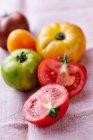 Various coloured tomatoes on a linen cloth, one halved — Foto stock