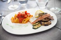 Tagliatelle with tomatoes and salmon fillet with grilled vegetables — Stock Photo