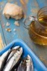 Fresh sardines in a blue Styrofoam dish with olive oil and bread — Stock Photo