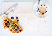 Xícara de café expresso e waffles belgas macios com mirtilos frescos e xarope de marple — Fotografia de Stock